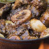 Traditional South African shin and oxtail beef potjie cooked over campfire with rich sauce and spices