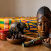 Traditional African souvenirs including wooden carvings, beaded jewelry, textiles, and South African food items representing cultural heritage and connection beyond trinkets
