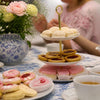 South African Sweet Treats displayed on a tiered stand, with iced pink cakes, jam biscuits and golden pastries.