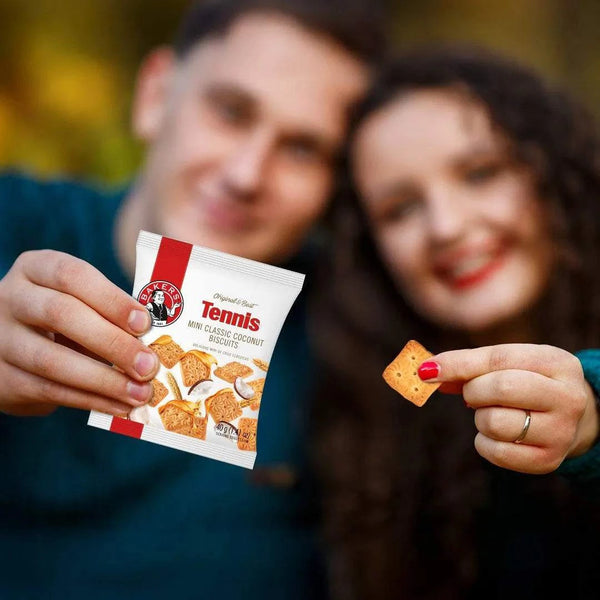 Bakers Tennis Mini Classic Coconut Biscuits 40g pack held by a smiling couple enjoying the crunchy coconut-flavored biscuits