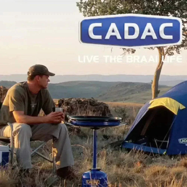 Outdoor scene featuring a CADAC Skottel Braai setup for camping, emphasizing versatile and portable gas BBQ cooking.