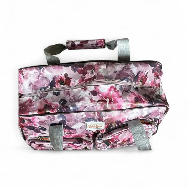 Light pink travel bag with purple rose print, large main zip pouch, and two small front zip pouches.