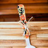 Enamel printed sugar spoon with colorful floral handle and wooden painted design tied with white string