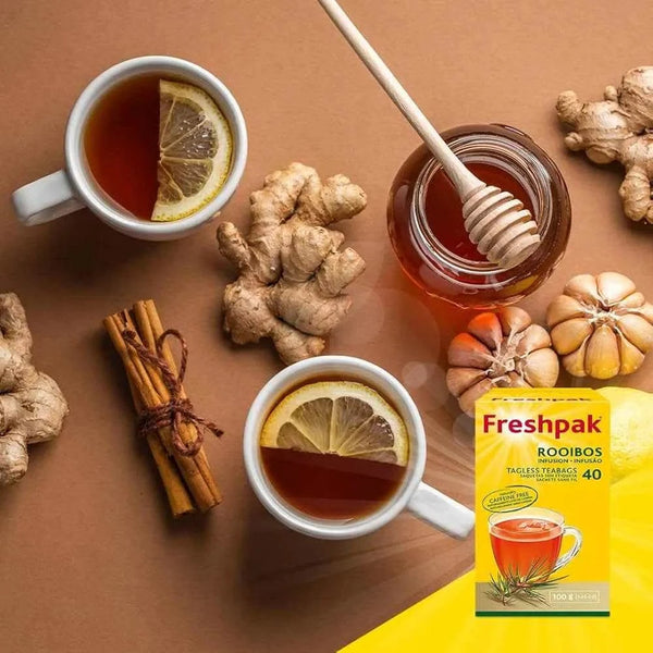 Freshpak Rooibos Tea 40's with lemon slices, honey, ginger, and cinnamon sticks on a brown background