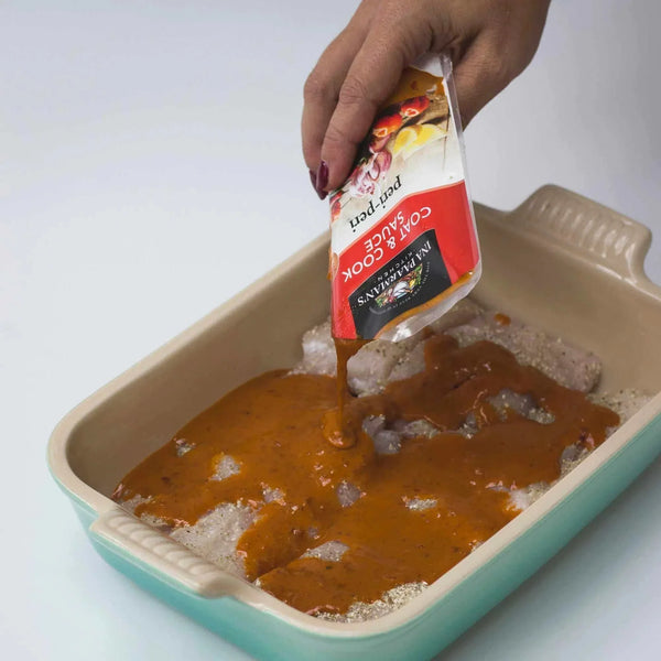 Ina Paarman Peri-Peri Coat & Cook Sauce being poured over chicken in a baking dish.