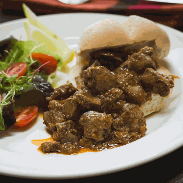 Peri-Peri coated meat with a roll and salad, showcasing Ina Paarman Coat & Cook Sauce.