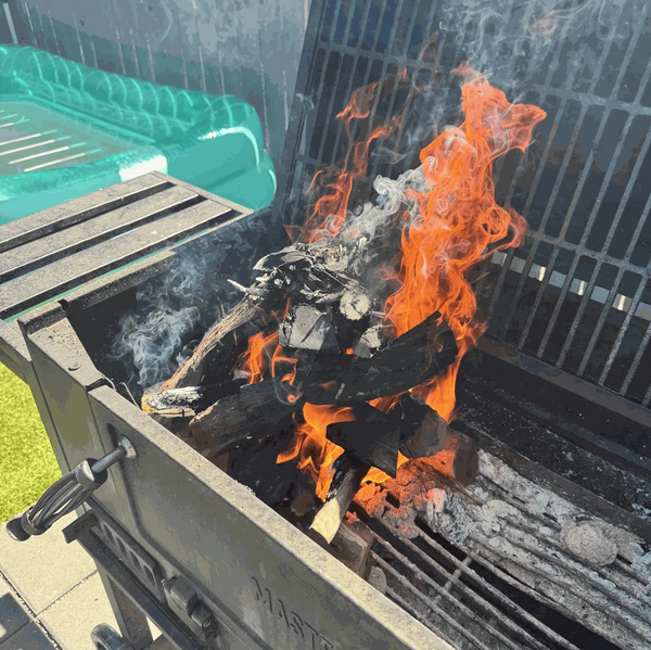 Burning Kameeldoring firewood in a grill, showcasing its low smoke and long-lasting heat.