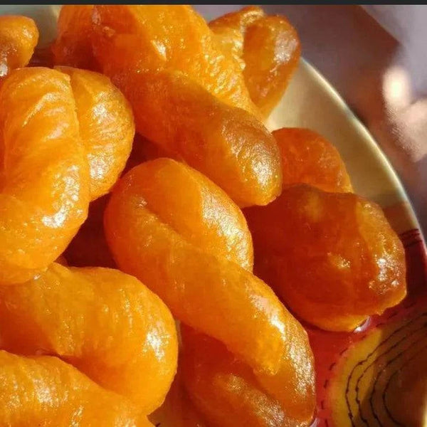 Close-up of golden fried South African Koeksisters soaked in syrup, ready-to-eat pack of 12 on a plate