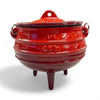 Red enamel traditional 3-legged cast iron pot with lid and handles, ideal for outdoor cooking.