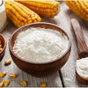 Maizena corn starch in wooden bowl with corncobs on a rustic table.