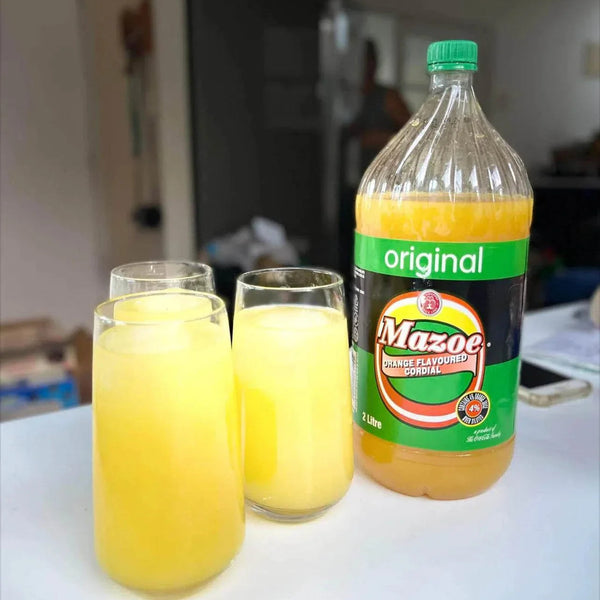 Mazoe Orange Crush - 2 Litre bottle with three glasses of citrus-flavored drink.