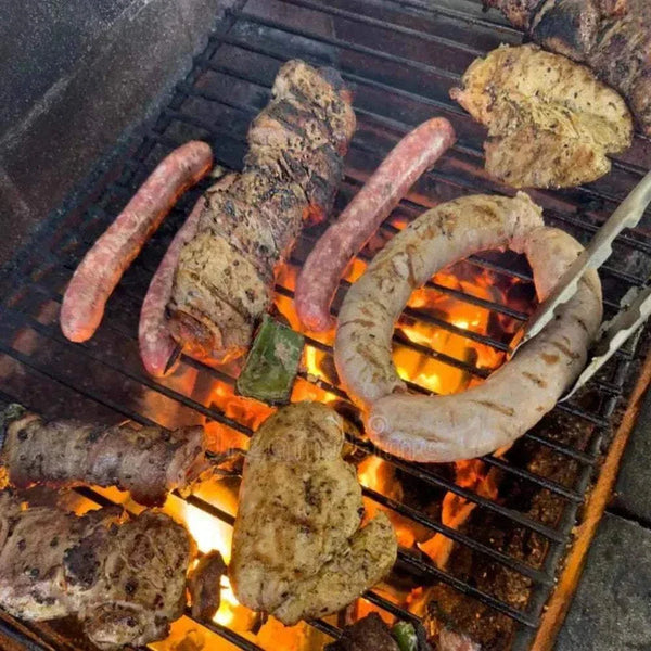 Grilled mixed meats and sausages cooking over open flame, enhanced with All Joy Meat Marinade flavors