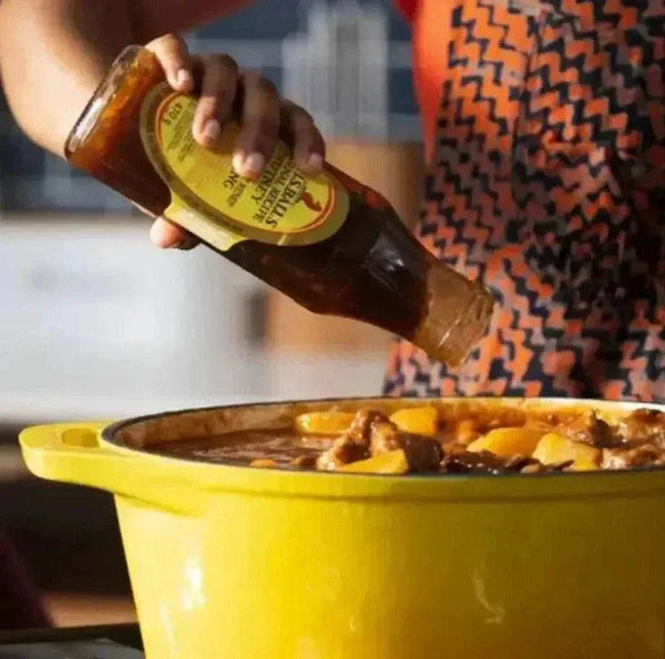 Mrs Balls Chutney Hot 470g being poured into a yellow pot, ideal for adding spice to meals.