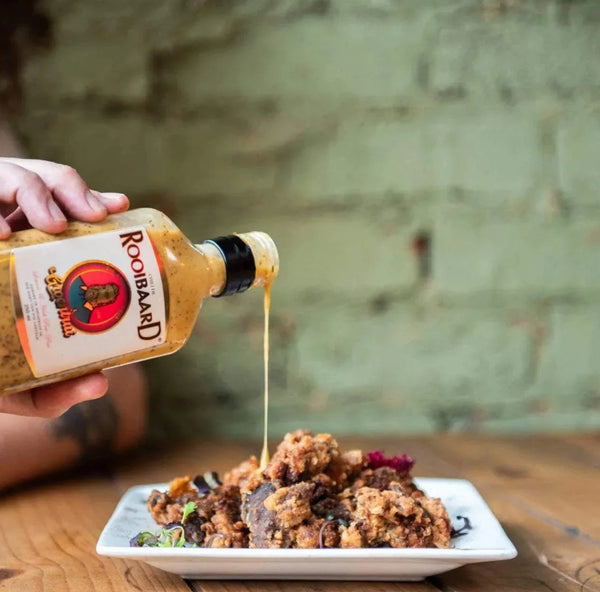 Rooibaard Groen Trui Chilli Sauce being poured onto food.