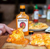 Rooibaard Groen Trui Chilli Sauce 250ml with pizza slice coated in sauce.