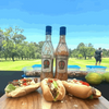 Rooibaard Groen Trui Chilli Sauce bottles with sandwiches outdoors.