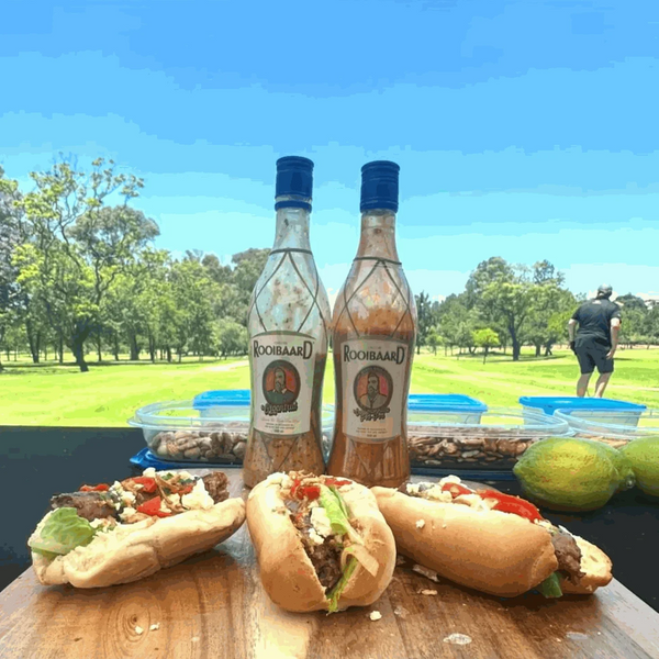 Rooibaard Groen Trui Chilli Sauce bottles with sandwiches outdoors.