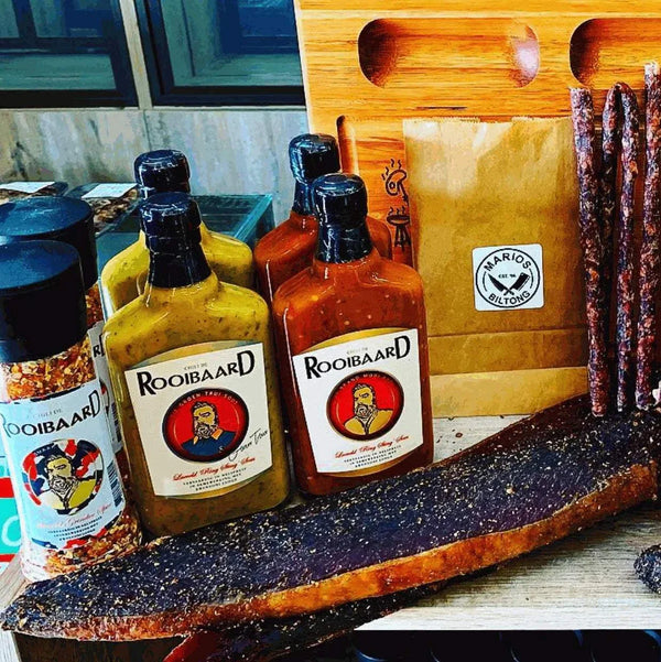 Rooibaard Kwaad Spice 170g with hot sauces and cured meats on display.