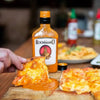 Rooibaard Original Peri Peri Sauce 550ml poured over pizza for a spicy flavor.