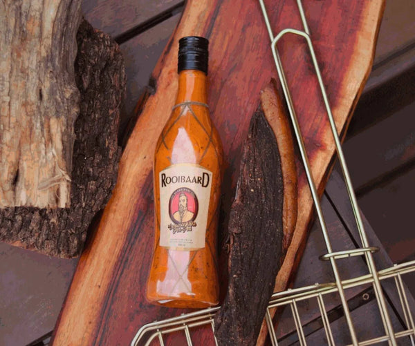 Rooibaard Original Peri Peri Sauce 550ml bottle on rustic wooden background.