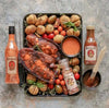 Rooibaard Original Peri Peri Sauce displayed with grilled meat, assorted roasted vegetables, and spices on a tray.