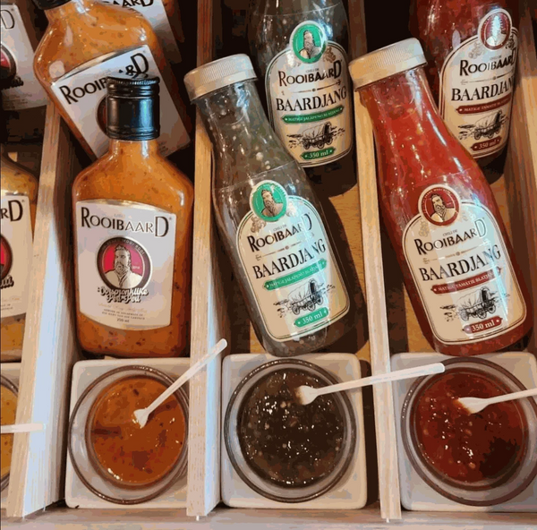 Rooibaard Sauce Baardjang Matige Jalapeno bottles displayed with sauce samples.