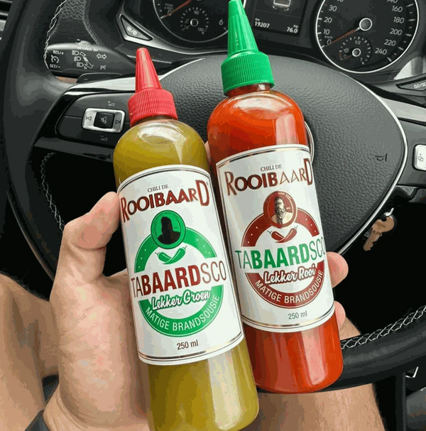 Rooibaard Tabaardsco Groen Sauce and Red Sauce bottles held inside a car.