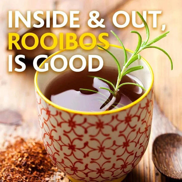 Cup of fresh rooibos tea with rosemary garnish and tea leaves on wooden surface