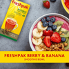 Freshpak Rooibos Tea box next to a berry and banana smoothie bowl with blueberries, strawberries, banana slices, kiwi, and granola on a gray surface