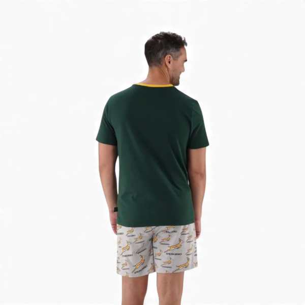 Man wearing 2XL Springbok Pajama Set with green short-sleeve top and white elastic waist shorts with Springbok logo pattern, back view