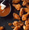 Tangy Spur Durky sauce glazed over chicken wings with a side bowl for dipping.