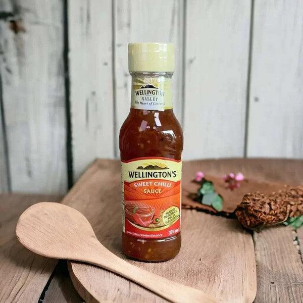 Wellington's Sweet Chilli Sauce 375ml bottle with wooden spoon on rustic wooden surface