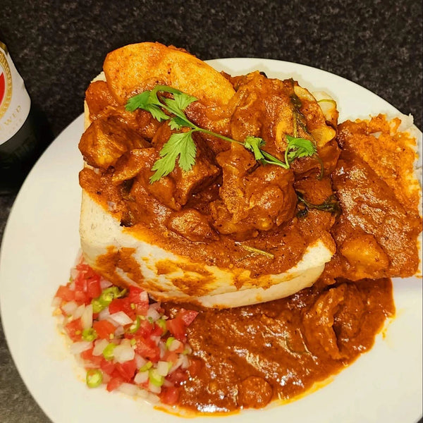 Durban Mutton Bunny Chow with spicy curry, bread, and fresh garnish on white plate
