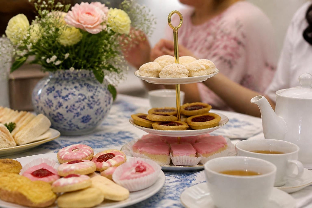 South African Sweet Treats displayed on a tiered stand, with iced pink cakes, jam biscuits and golden pastries.