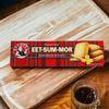 Bakers Eet-Sum-Mor 200G shortbread biscuits on a wooden table next to a cup of tea.