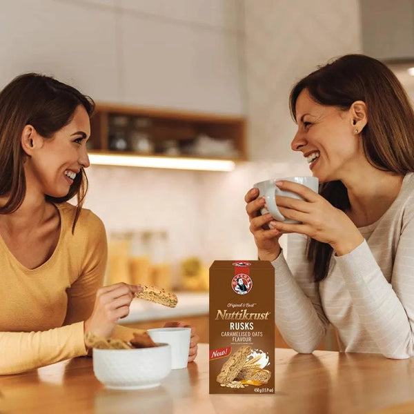 Nuttikrust caramelised oats rusks 450g box with two women enjoying rusks and tea at kitchen table