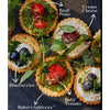 Bakers Salticrax Salted Crackers topped with cream cheese, basil pesto, blueberries, and baby tomato.
