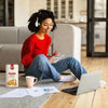 Bakers Tennis Classic Coconut Rusks 450g beside a woman enjoying coffee while using a laptop.
