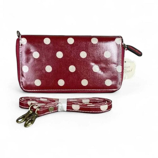 Red sling wallet with large white polka dots and removable shoulder strap