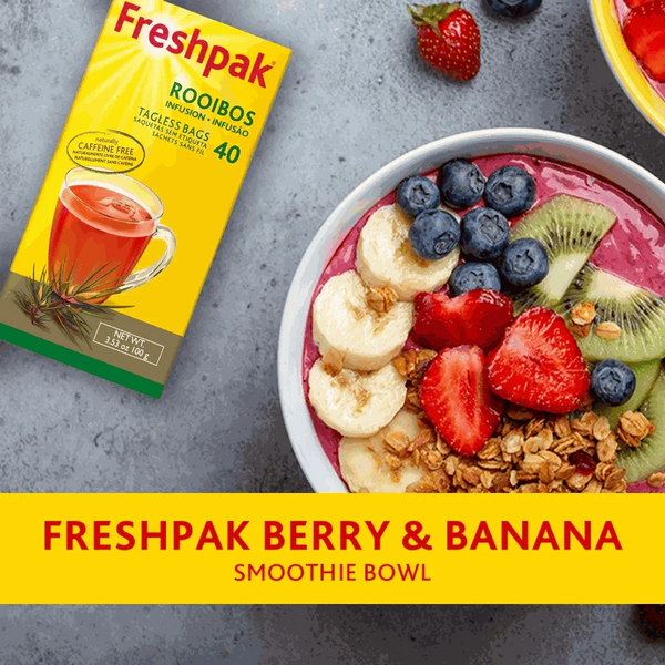 Freshpak Rooibos Tea box next to a berry and banana smoothie bowl with blueberries, strawberries, banana slices, kiwi, and granola on a gray surface