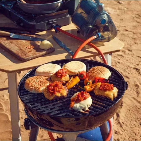 Portable CADAC Carri Chef 40 gas BBQ with built-in thermometer, grilling burgers outdoors.