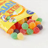 Beacon Jelly Tots Original 100gr - colorful, sugar-coated, fruit-flavored candy pieces spilling from a yellow package.