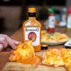 Rooibaard Original Peri Peri Sauce 550ml poured over pizza for a spicy flavor.