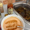 Rooibaard Sauce Baardjang medium-spiced tomato sauce in 350ml bottle next to bowl of mixed sauce with paprika and a sink with soaking crabs