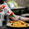 Rooibaard Tabaardsco Rooi Sauce being poured onto fries and chicken, showcasing its vibrant red color and easy squeeze bottle.