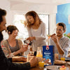 Bakers Romany Classic Choc Coconut Flavour Rusks 450g on a breakfast table with people enjoying snacks and drinks.
