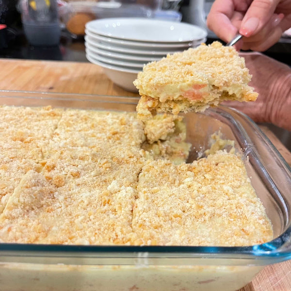 Glass dish of baked crumbly dessert with guava halves.