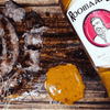 Rooibaard Sauce Basting “Meat Paint” 375ml on wooden board with sausage and sauce blob.