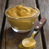 Wimpy Mustard Sauce in a glass bowl with a spoon on wooden surface.